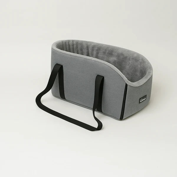Small brown poodle puppy inside a black shoulder travel carrier bag with grey fleece lining.