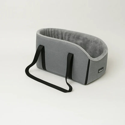 Small brown poodle puppy inside a black shoulder travel carrier bag with grey fleece lining.